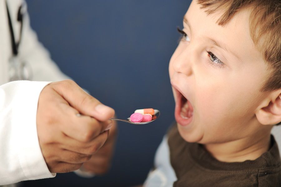 Doctor giving a child a spoon filled with pills