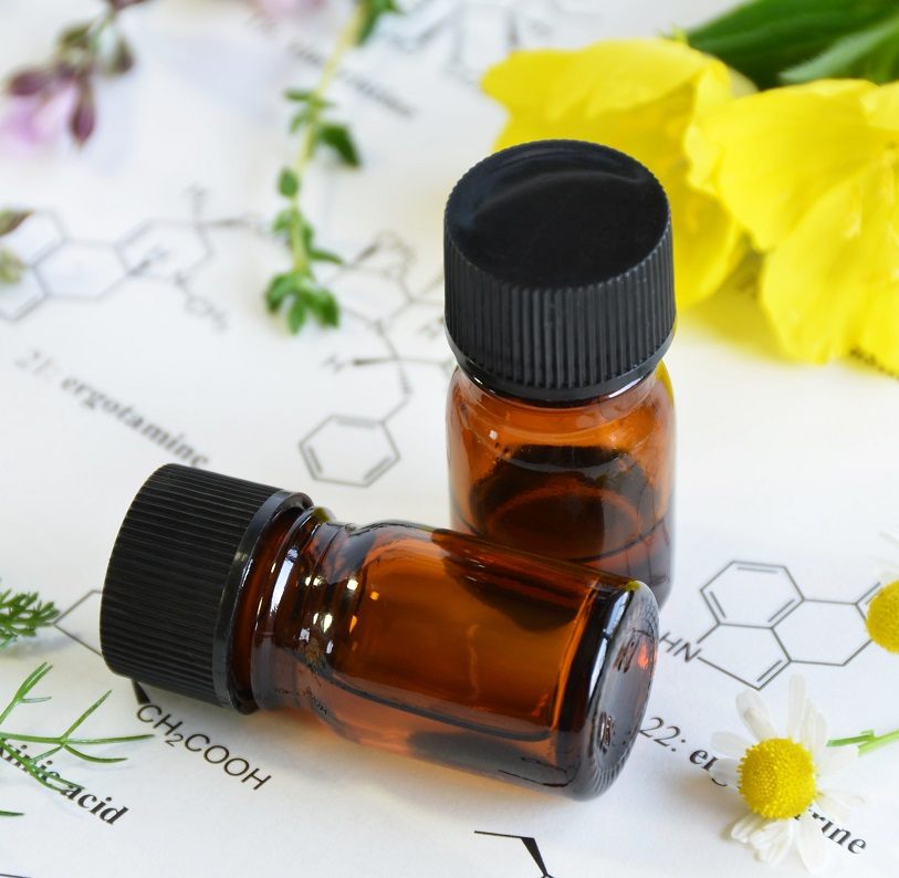 essential oils with herbal flowers on science sheet
