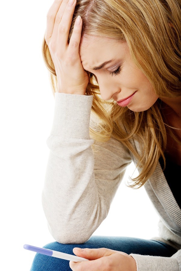 Sad young woman holding pregnancy test feeling hopeless