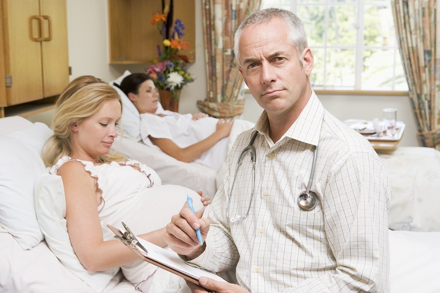 Doctor sitting by pregnant women holding chart