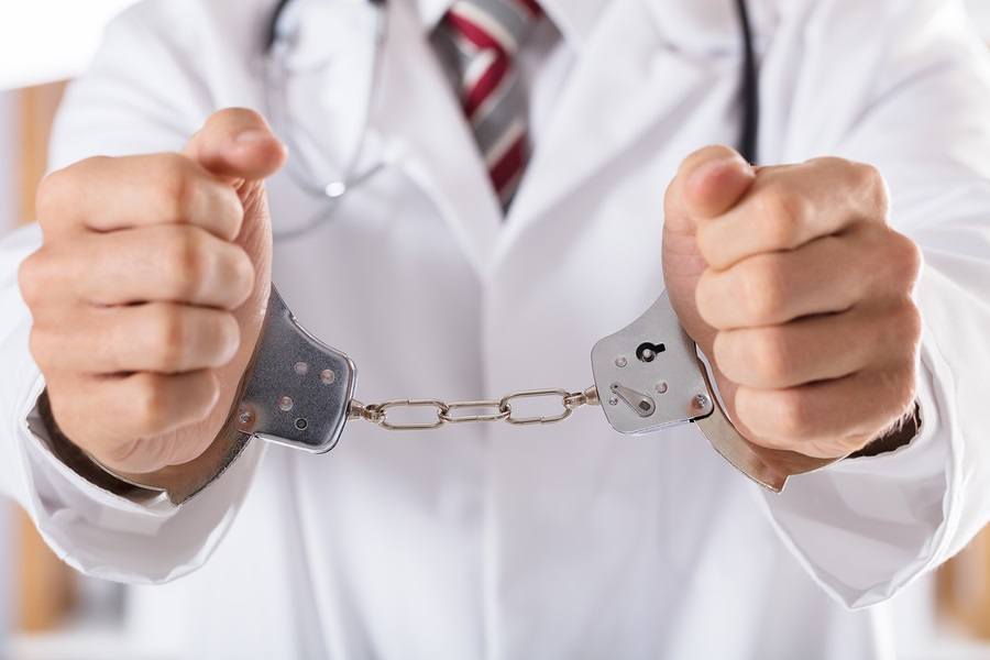 Close-up Of Arrested Doctor's Hand With Handcuffs