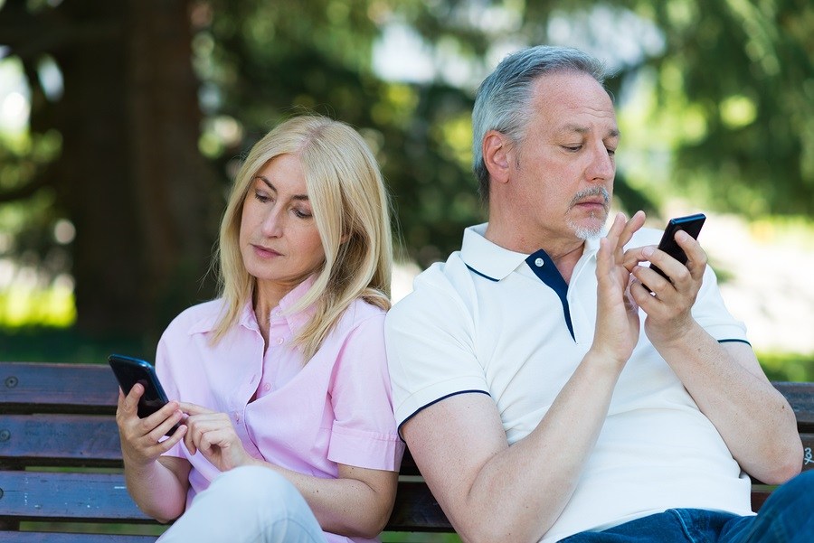 Mobile phone addiction concept - couple looking at their mobile phone and ignoring each other
