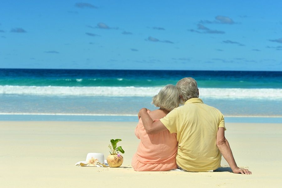 Elderly couple sitting on the shore and looks at sea