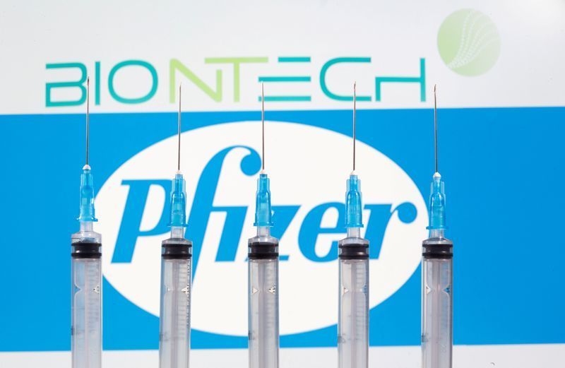 FILE PHOTO: Syringes are seen in front of displayed Biontech and Pfizer logos in this illustration