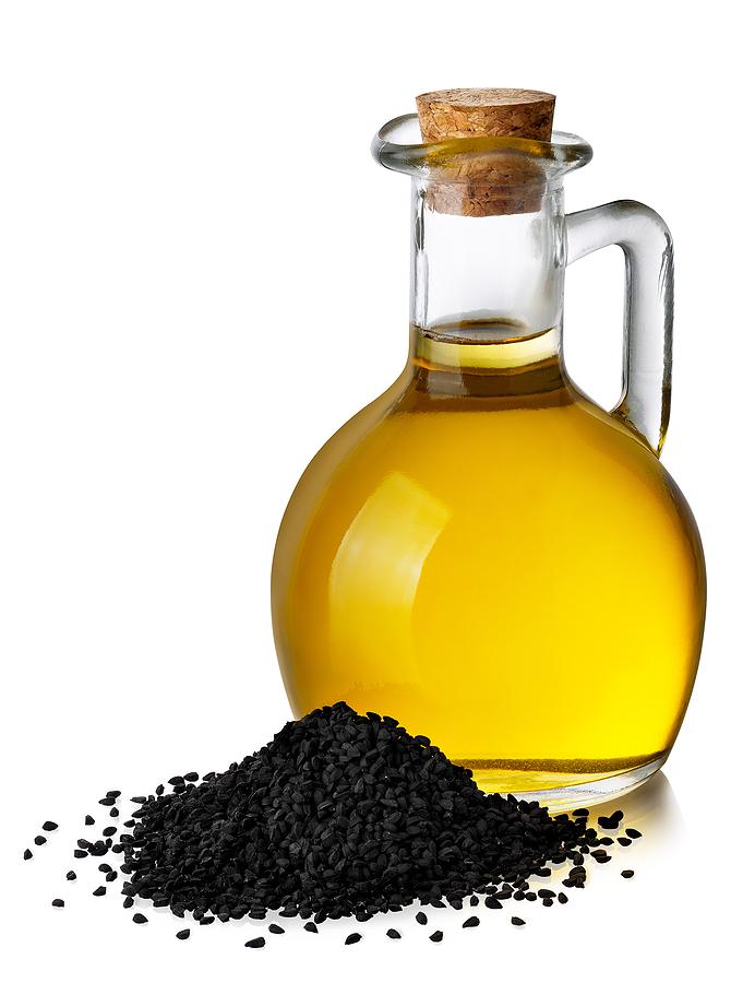 Black Cumin Oil In Glass Bottle And Heap Of Seeds Isolated On Wh